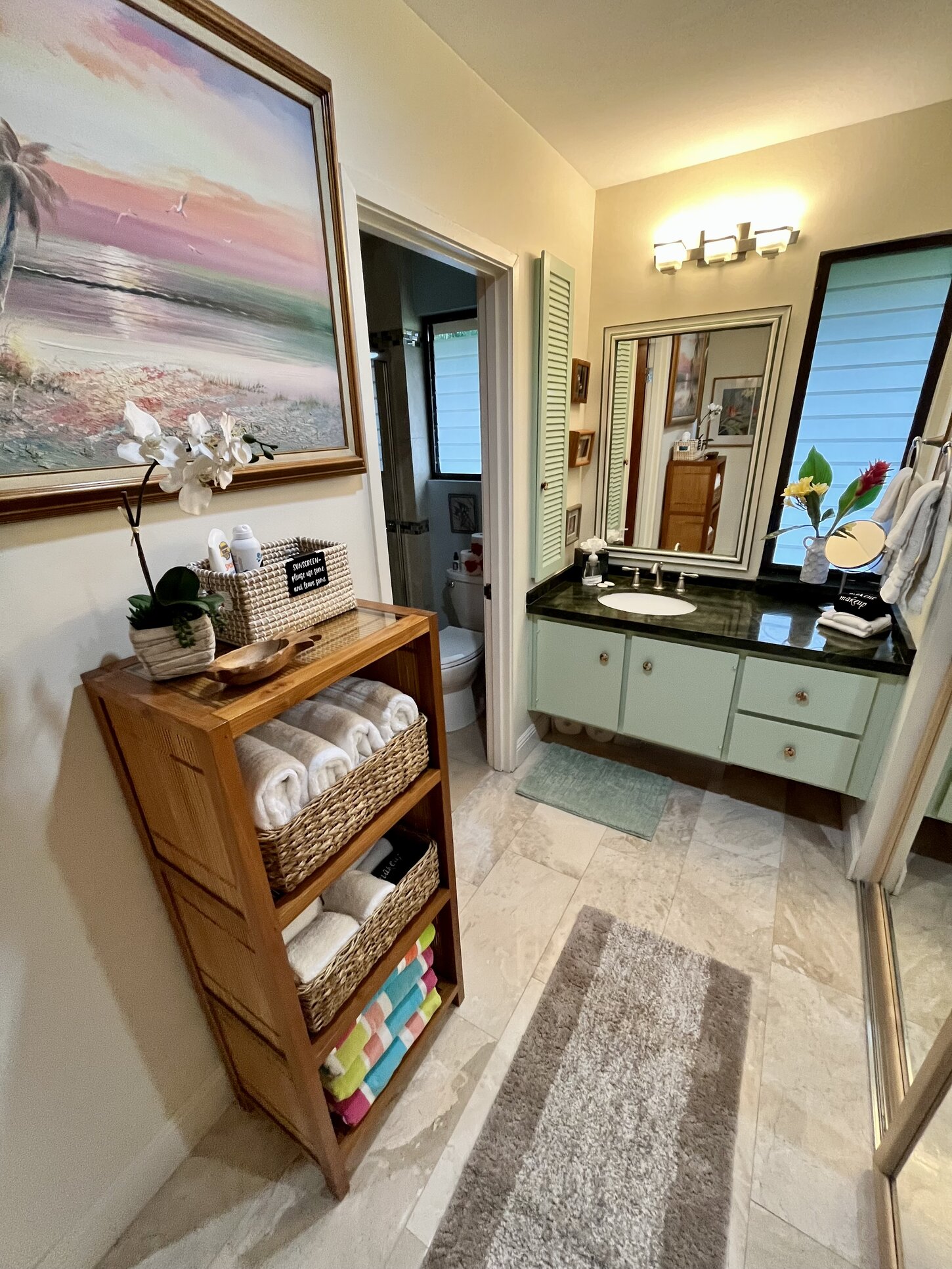 Bathroom sink area, just outside the shower and toilet, featuring a towel center with island-inspired touches. A perfect space to refresh with tropical flair! A perfect spot to get ready for your day in paradise