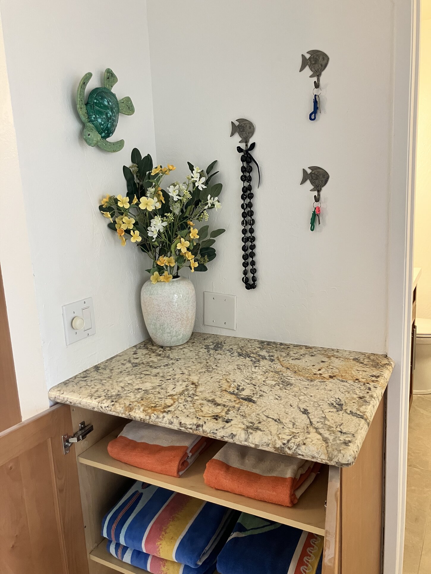 Entryway counter with keys, above on hooks, and beach towels below