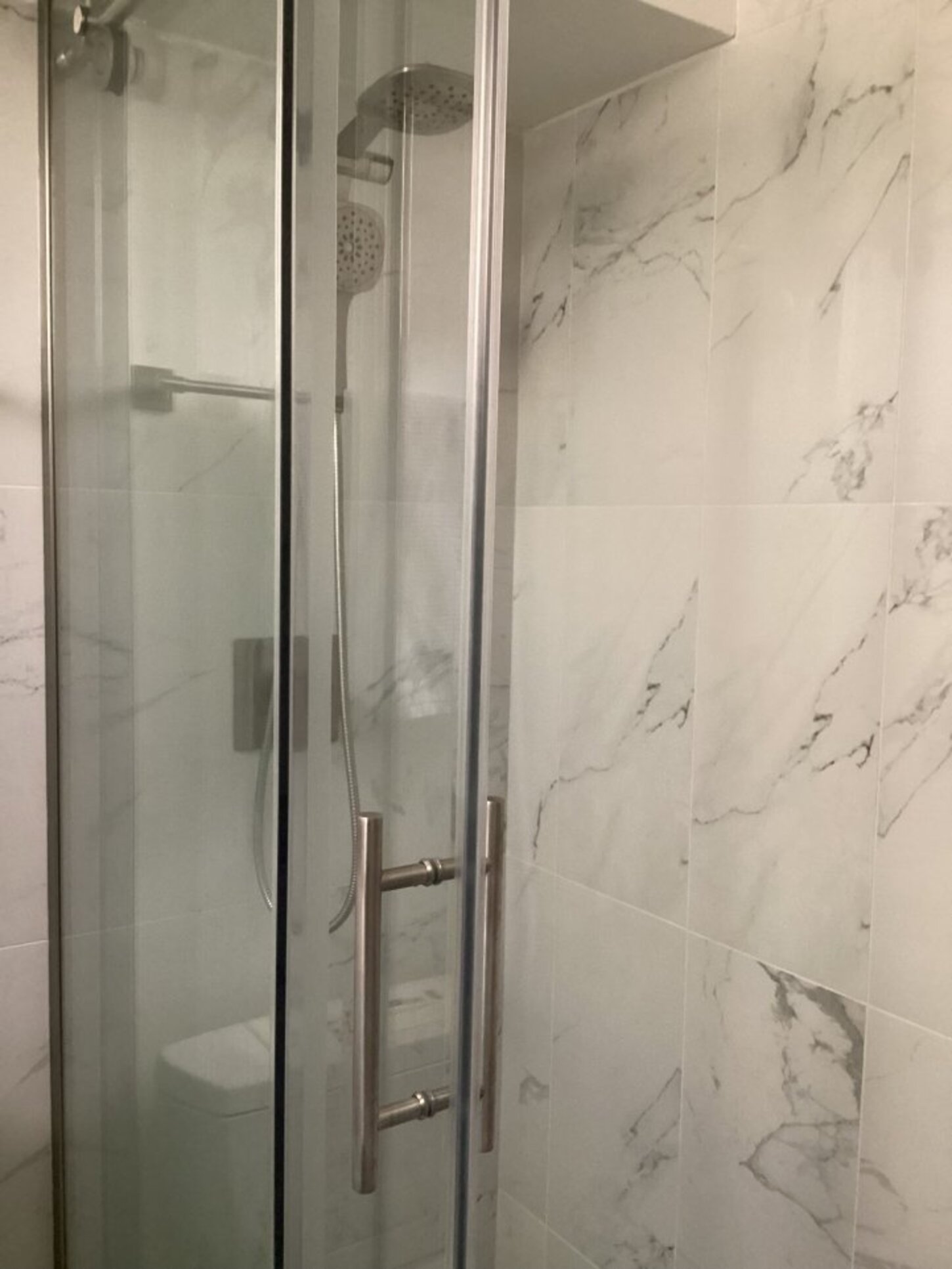 Primary shower with glass doors and Carrara tile